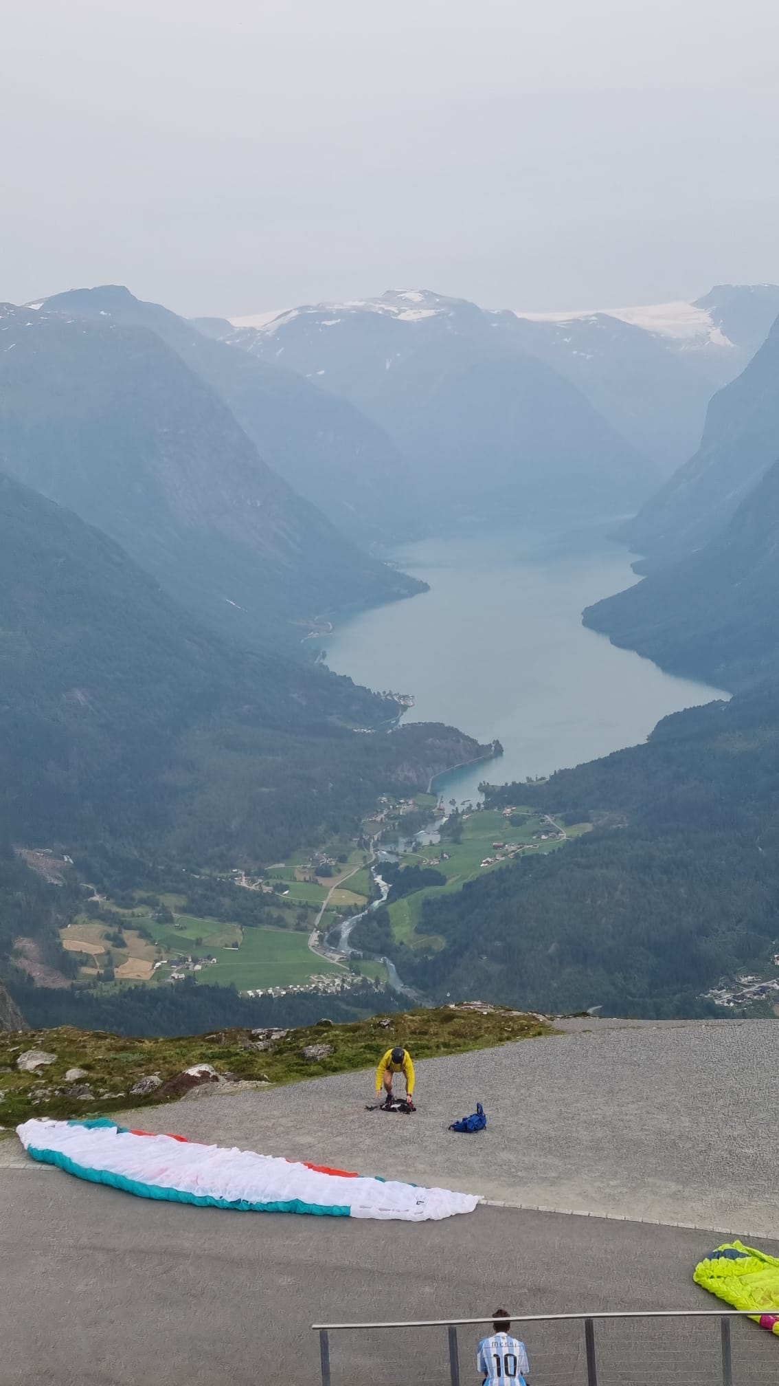 A paraglider preparing to launch from the summit of Mount Hoven above the fjord