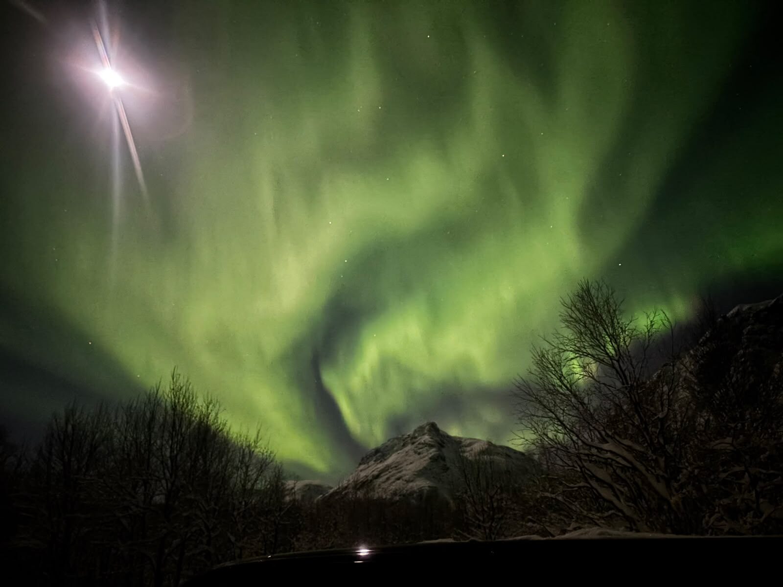 Northern lights above a snow-covered peak on a moonlit night